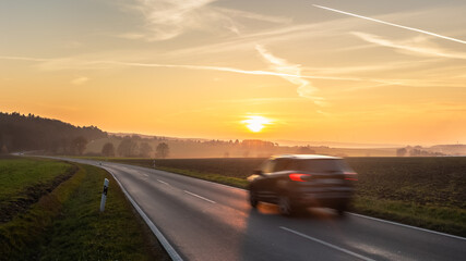 Fototapeta premium car driving on the road at sunset