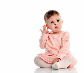 pensive, thoughtful little girl in cute pink stylish warm clothes sits, holds her hand near her ear...