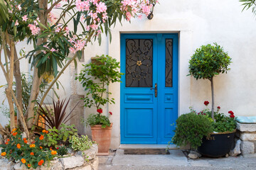 Fototapeta na wymiar Beutiful vintage courtyard with lush greenery and marine blue wooden door in old Mediterranean costal town, Croatia.