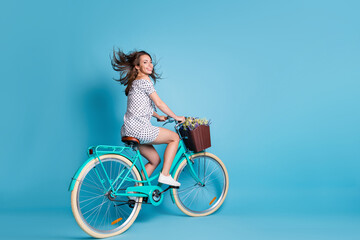 Full length profile photo of girl ride bike pot flowers wear dotted short dress sneakers isolated blue color background