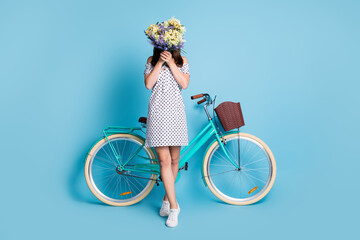 Full length photo of shy girl hide face bouquet wildflowers bike wear dotted mini dress footwear...