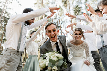 bride and groom run among the company of friends, wedding day of a beautiful couple, holiday of...