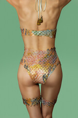 Rear view of a woman's body, wearing a fish scale textured pastel color silicone swimsuit