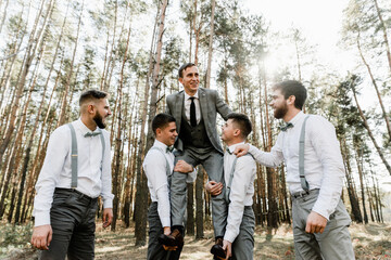 friends lift a happy groom on their shoulders, a group of friends laughs and have fun, happy people,handsome groom with lovely friends smiling