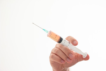 Caucasian male hand holding a syringe with needle and orange serum close up shot isolated on white
