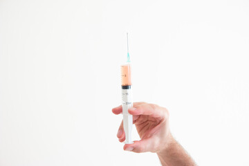 Caucasian male hand holding a syringe with needle and orange serum close up shot isolated on white