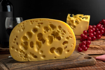 artisan cheeses with dried fruits glass of wine, homemade country bread, bunch of grapes, on wooden board with knife