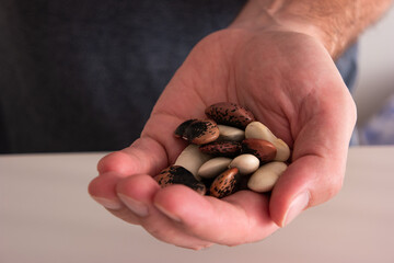 Caucasian male hand holding an assortment of uncooked dry beans close up shot