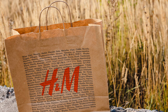 H and M (international chain of mass fashion retail clothing stores) paper eco friendly shopping bag staying on natural background. Brand refused using plastic bags.