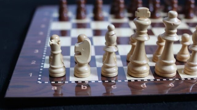 wooden white and black chess pieces on the board. blurry background.