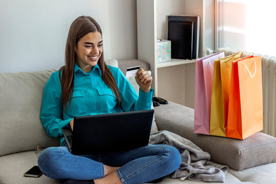 Happy smiling girl using laptop and credit card. Happy woman shopping online with laptop at home. Girl using laptop computer shopping online. Shot of a young woman cheering while using laptop at home