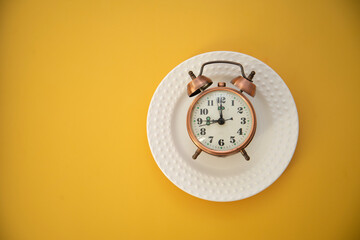 clock on the white plate on yellow background.