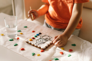 A child paints glazed gingerbread cookies with food coloring. Creativity and hobbies