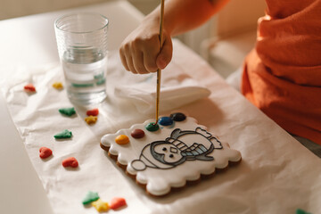 A child paints glazed gingerbread cookies with food coloring. Creativity and hobbies