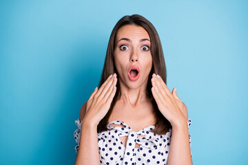 Photo of surprised young lady open mouth hands face staring camera wear dotted blouse isolated blue color background