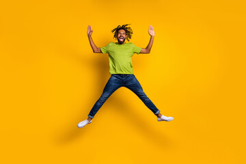 Fototapeta na wymiar Full length photo portrait of excited guy jumping up spreading arms legs like star isolated on vivid yellow colored background