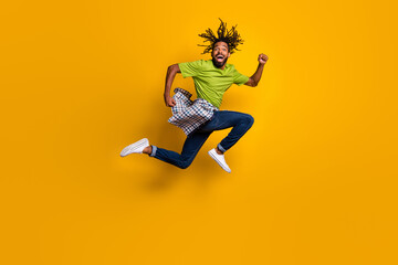Fototapeta na wymiar Full length photo portrait of laughing runner jumping up isolated on vivid yellow colored background