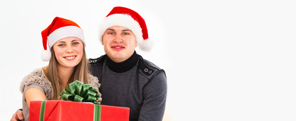 Young couple in christmas santa hats giving a gift