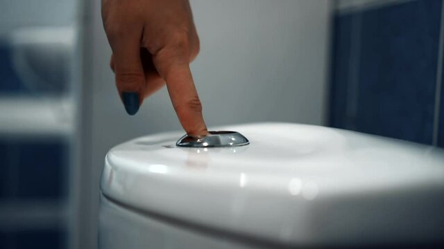 a female hand presses the toilet cistern