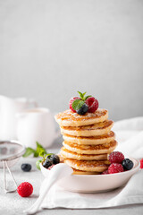 homemade pancakes with fresh berries and honey on a white plate