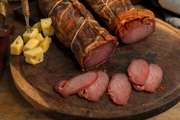salami, sausages with herbs and cheese cut into slices on wooden board, homemade bread, nuts