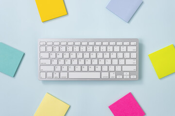 White Portable Computer Keyboard Keys or Keyboard Button and Colorful Stick Note or Note Pad on Blue Pastel Minimalist Background