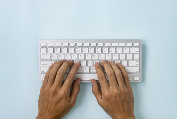 Hand of Businessman Typing Portable Computer Keyboard Keys or Keyboard Button on Top Table or Top View on Blue Pastel Minimalist Background