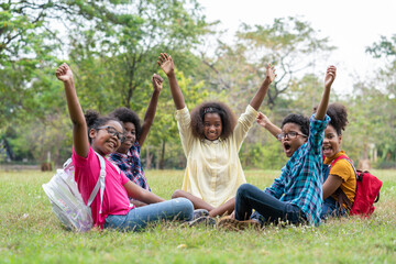 Happy fun group of African American children raised hands together in the park, Education outdoor concept