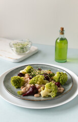 Natural salad of mini beets, romanesco cabbage, white beans and sprouted onion seeds on a gray...