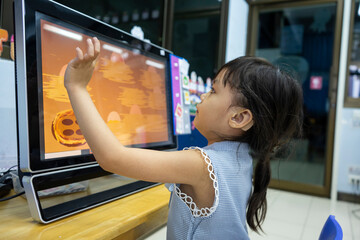 A girl wearing a hearing aid is learning by computer