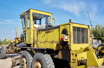 Road grader - heavy earth moving road construction equipment. Industrial motor grader on ground