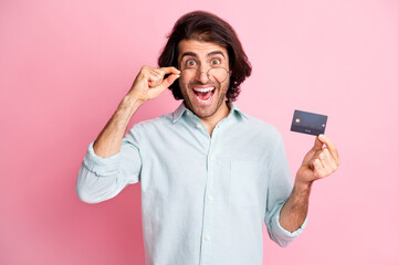 Portrait of young handsome excited happy man male guy hold credit card wear glasses isolated on pink color background