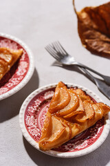 Slices of Homemade French Apple Tart or Pie on plates on light concrete background