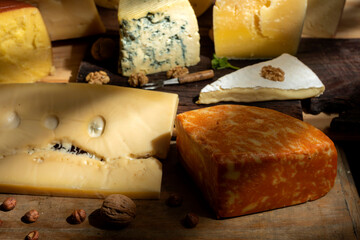 
variety of cheeses together with nuts illuminated with light from a window, with wood still life photo