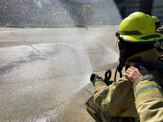 A fireman in a fire fighting equipment with oxygen cylinders to suppress the fire. And spraying...