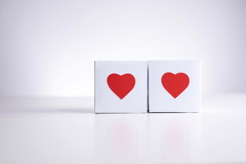 Two white boxes with red hearts  on a white background, close up, copy space.