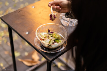 Beautiful woman eating takeaway salad on city street. Food concept