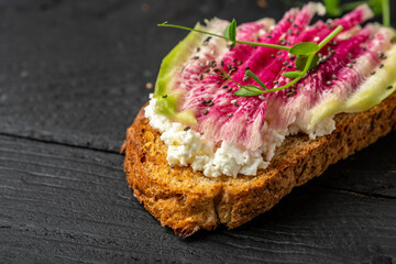 Bruschetta with goat cheese, watermelon radish, microgreen and chia seeds, Healthy breakfast toasts from sliced watermelon radish or chinese daikon. Food recipe background. Close up