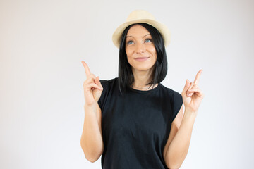 Obraz na płótnie Canvas Young brunette woman with blue eyes wearing casual t-shirt and straw hat over isolated white background pointing up with fingers and raised arms.