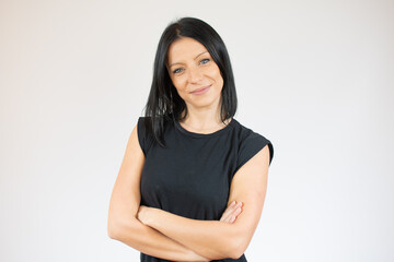 Obraz premium Portrait of a smiling young woman in casual black t-shirt with arms folded isolated over white background