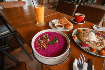 Healthy breakfast bowl - bowl with dragon fruit with granola, pancakes and mango juice