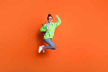 Fototapeta na wymiar Full length photo portrait of cheerful girl celebrating jumping up isolated on vivid orange colored background