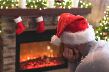Sad man in Santa Claus hat in a depression feeling negative emotions during christmas celebrations