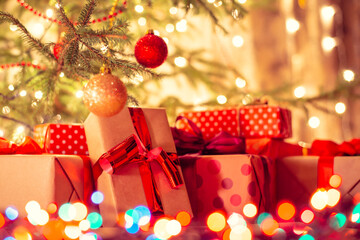 Christmas presents wrapped in colorful parchment paper under Christmas tree with bright christmas lights. Christmas celebration