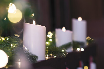 Selective focus of burning candle in Christmas decoration with light bokeh. Close up