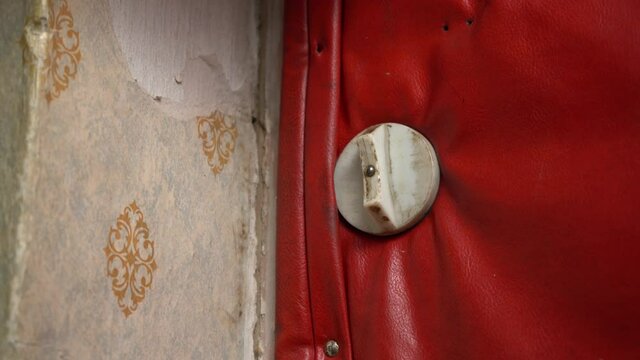 Close the old door from the inside. A man's hand closes a wretched old door covered with red dermantine. Close in a squalid apartment