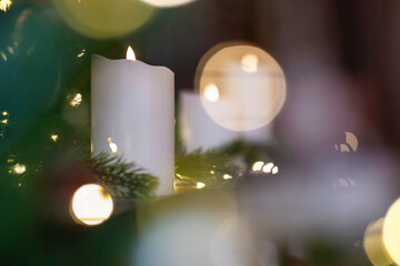 Selective focus of burning candle in Christmas decoration with light bokeh. Close up