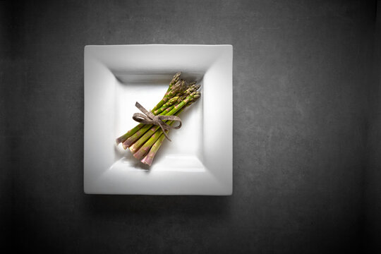 A bundle of fresh green asparagus on a porcelain plate