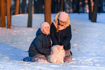 Beautiful teenage girls having fun with spitz dog in winter