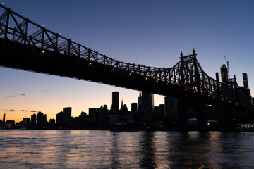 Fototapeta na wymiar The Queensboro Bridge with a Silhouette of the Manhattan Skyline during Sunset along the East River in New York City